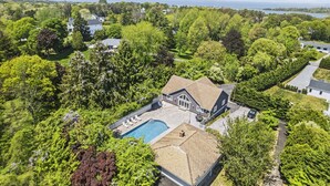 A large house with a swimming pool, surrounded by dense greenery and a view of the sea. - Southampton 4BR Home | Pool, Game Room (Southampton)