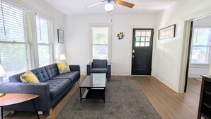 Een woonkamer met een bank, fauteuil, salontafel en een deur.