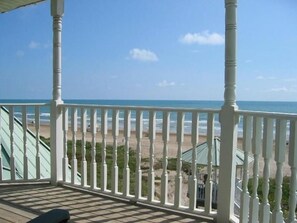 Une terrasse en bois avec des balustrades blanches donnant sur une plage.
