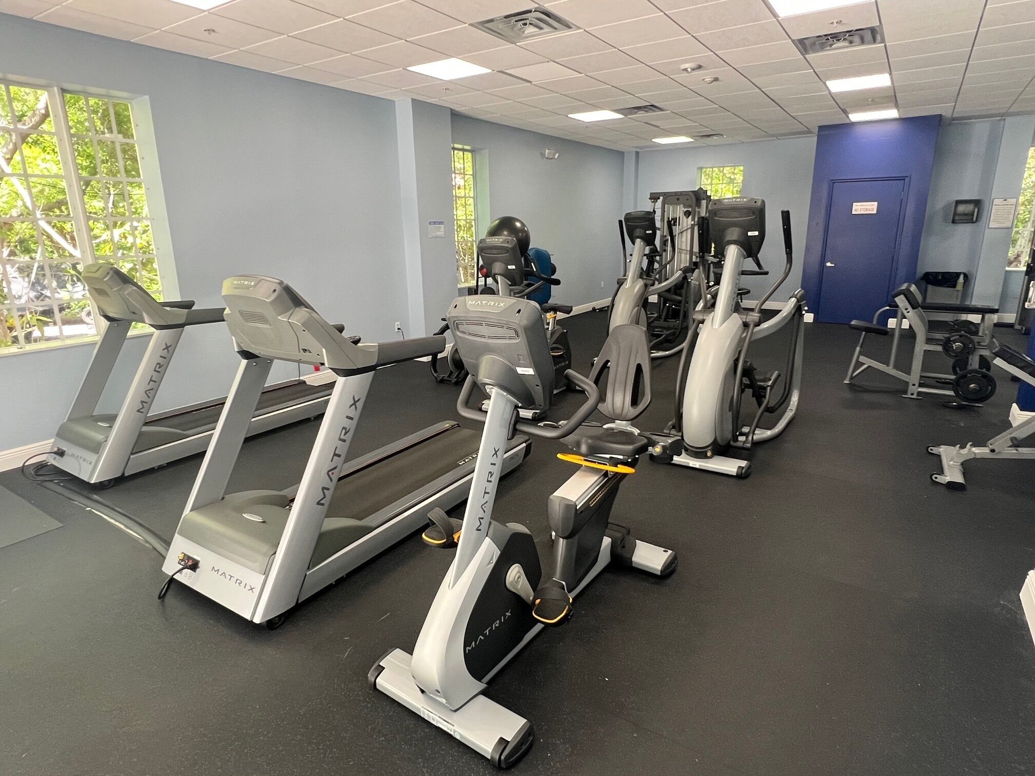 Un gimnasio con cintas de correr, elípticas y equipo de pesas.