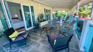 A covered outdoor area with seating, a small table, and a bed with sliding glass doors. - Private Villa & Apartment with Pool in Palm Beach! (Noord)