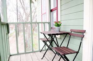 A covered porch with a wooden table and two chairs, a potted plant, and a view of a yard with trees. - 2BD/1BA - The Treehouse - 1930's Hyde Park Home by UT/Downtown (Austin)