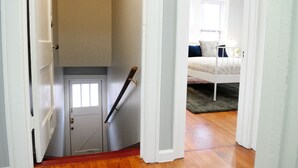 Une chambre à coucher avec un lit, une fenêtre et une porte donnant sur un escalier.