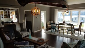 A spacious living room with a dark ceiling, a dining area with a view, and a kitchen visible through an open door. - 5 minutes to Peek n Peak, ON SITE PRIVATE HOT TUB, Large private yard (Clymer)