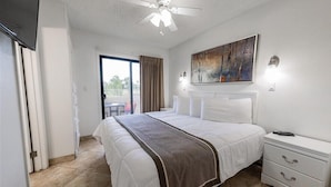 A hotel room with a bed, a ceiling fan, a painting, a nightstand, and a view of the outdoors. - 118 Luxury Getaway in Scottsdale | Spacious Suite, Outdoor Entertainment & Heated Pool (Scottsdale)