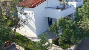 Et moderne hus med to etager, rødt tegltag, solpaneler og en balkon.