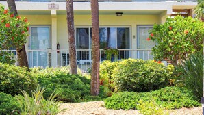 A two-story building with a yellow facade, large windows, and a balcony with outdoor seating. - Unique Pass-a-Grille condo just steps from the sand.. (St Pete Beach)