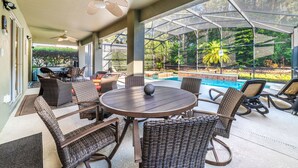 Un patio couvert, aménagé avec des meubles en osier, une piscine et une vue sur l’extérieur.