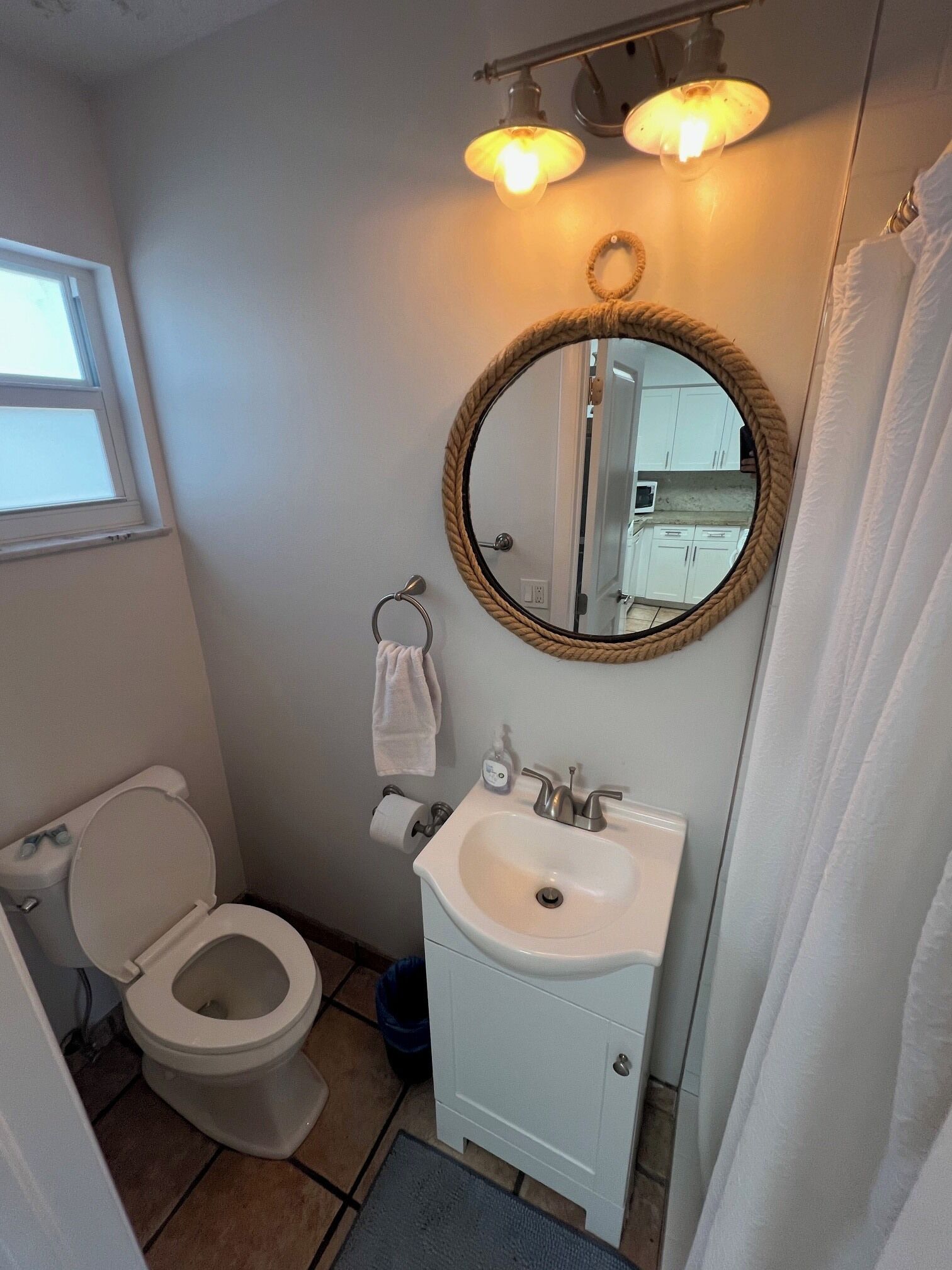 A bathroom with a toilet, sink, mirror, and towel rack.