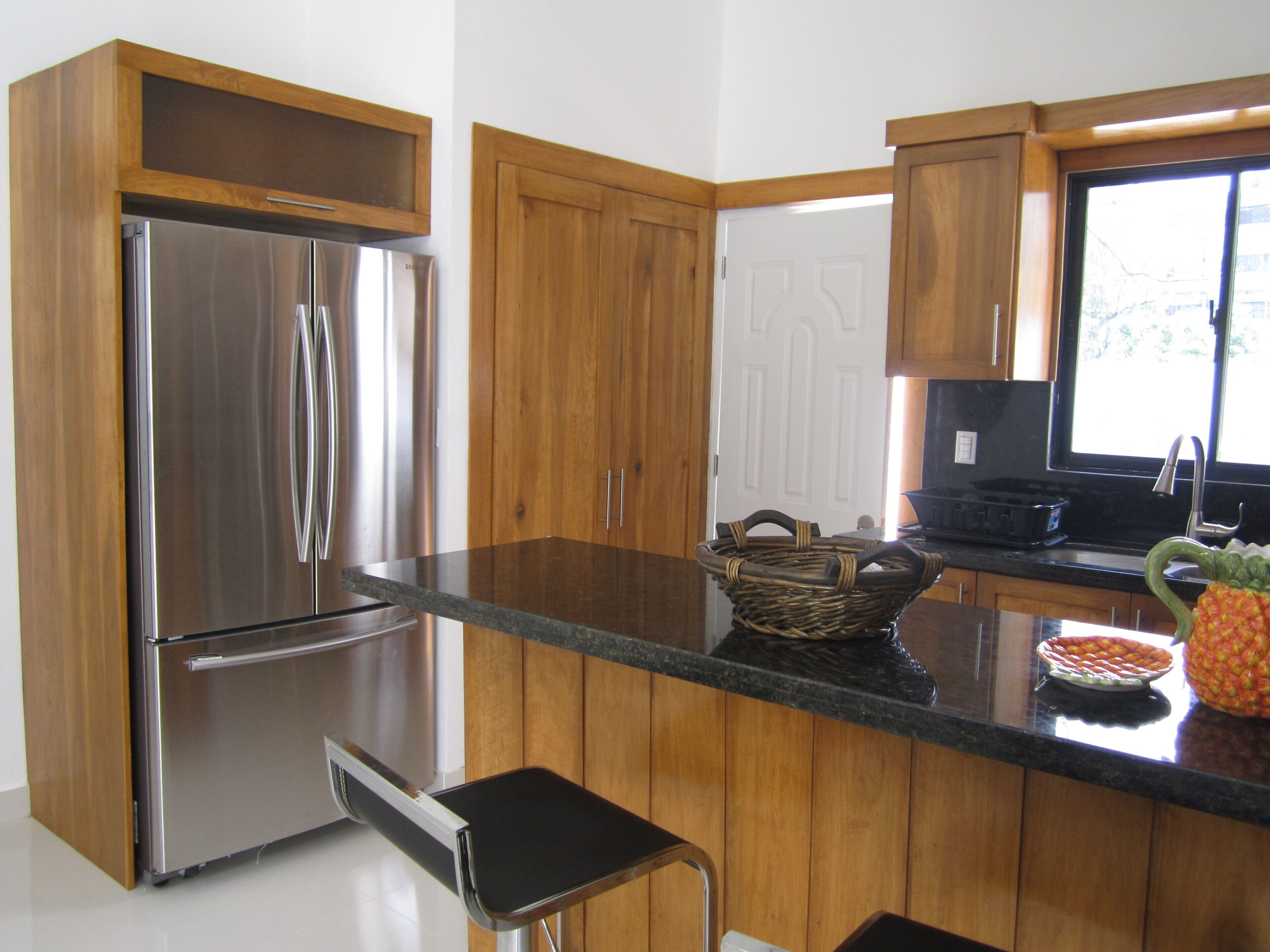 A modern kitchen with stainless steel appliances, wooden cabinets, and a black countertop.