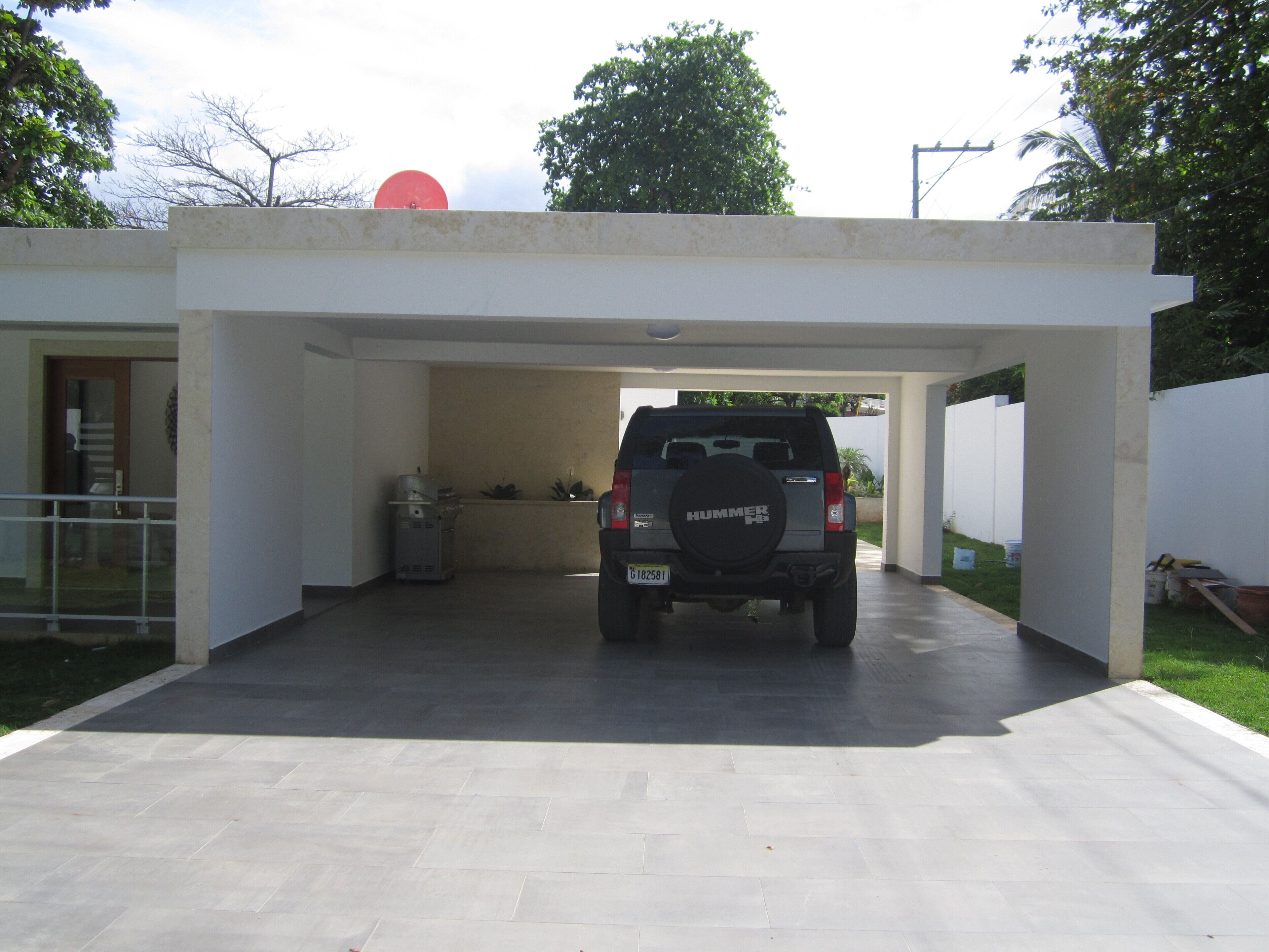 Un edificio moderno dotato di area parcheggio coperta e un'auto parcheggiata all'interno.