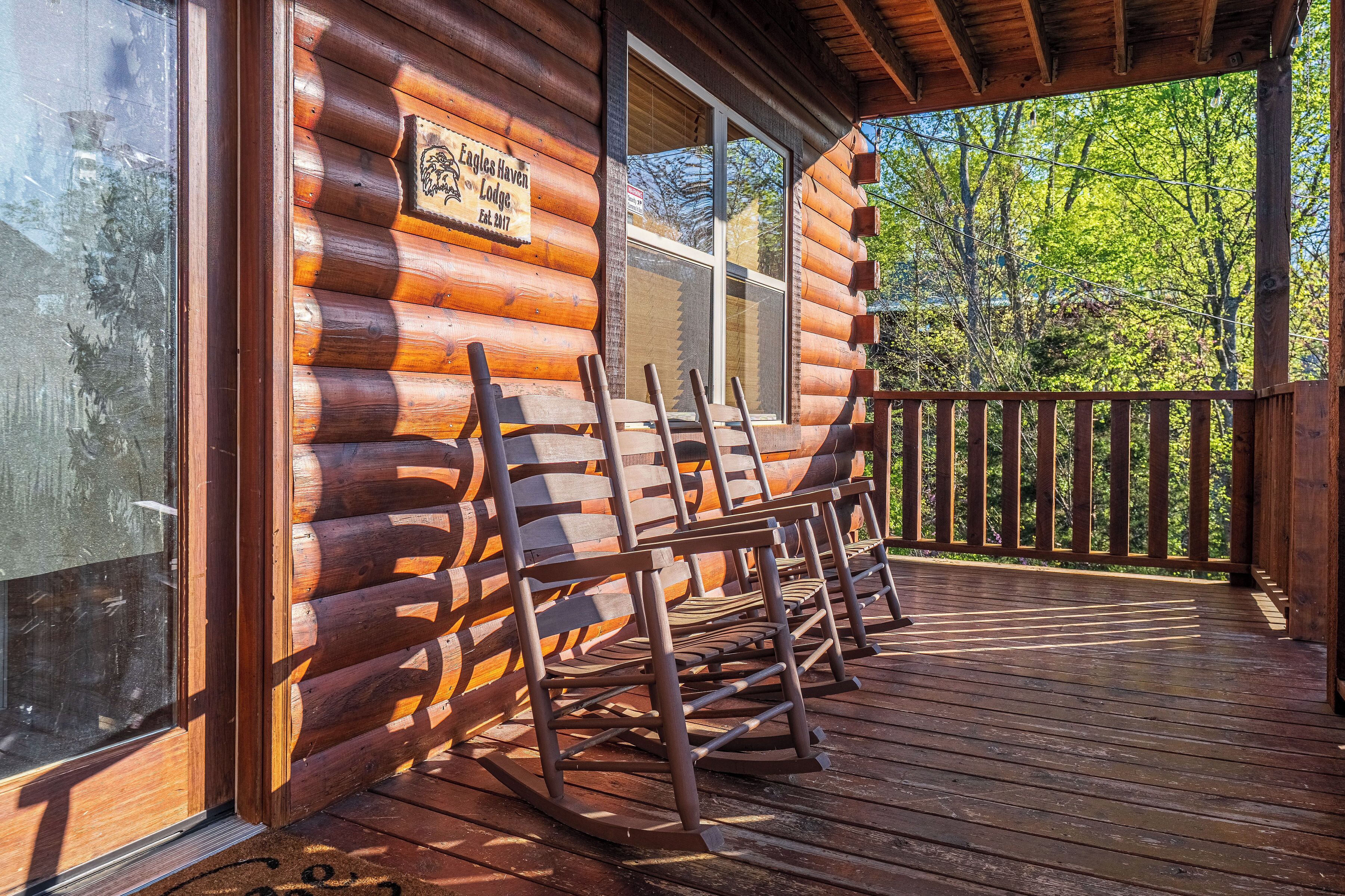 A log cabin with a porch, rocking chairs, and a sign indicating it is Eagle Haven Lodge.