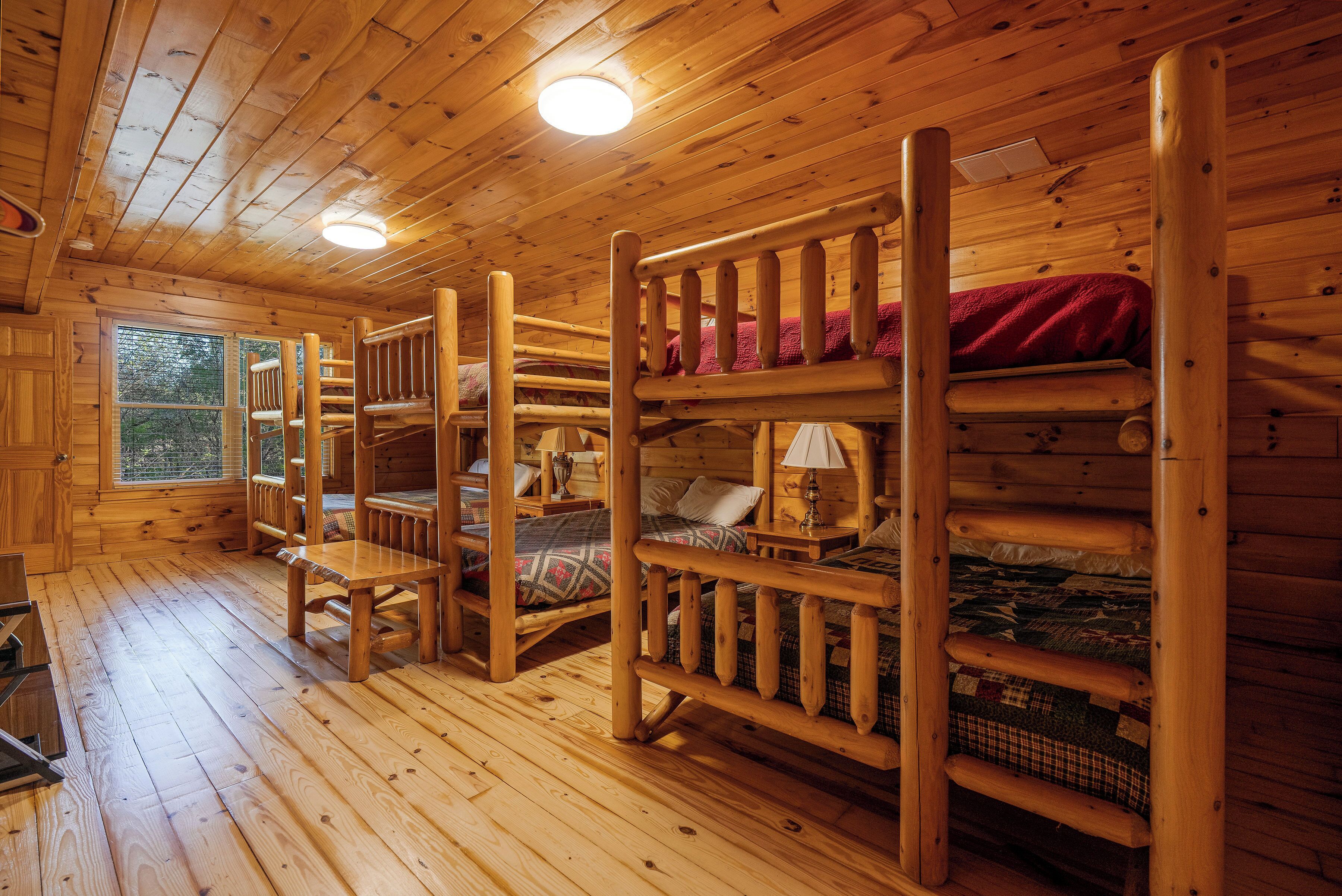 A cabin with wooden bunk beds, a window, and a wooden floor.