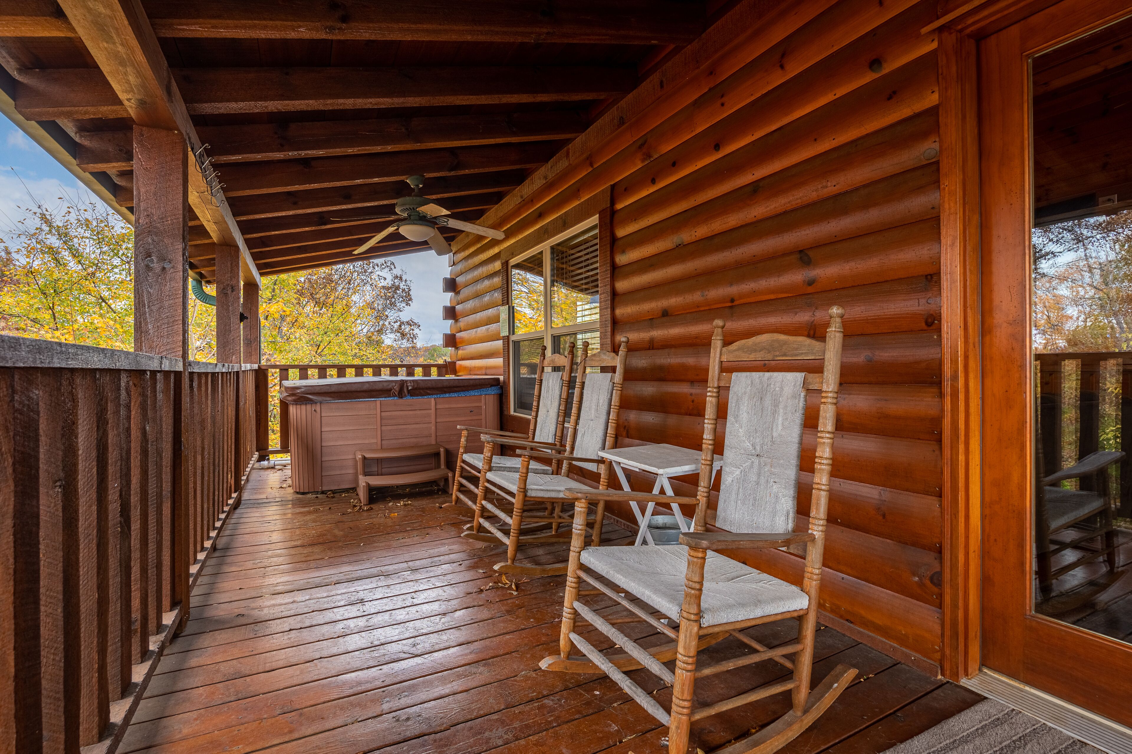 Een houten terras met schommelstoelen en een jacuzzi.
