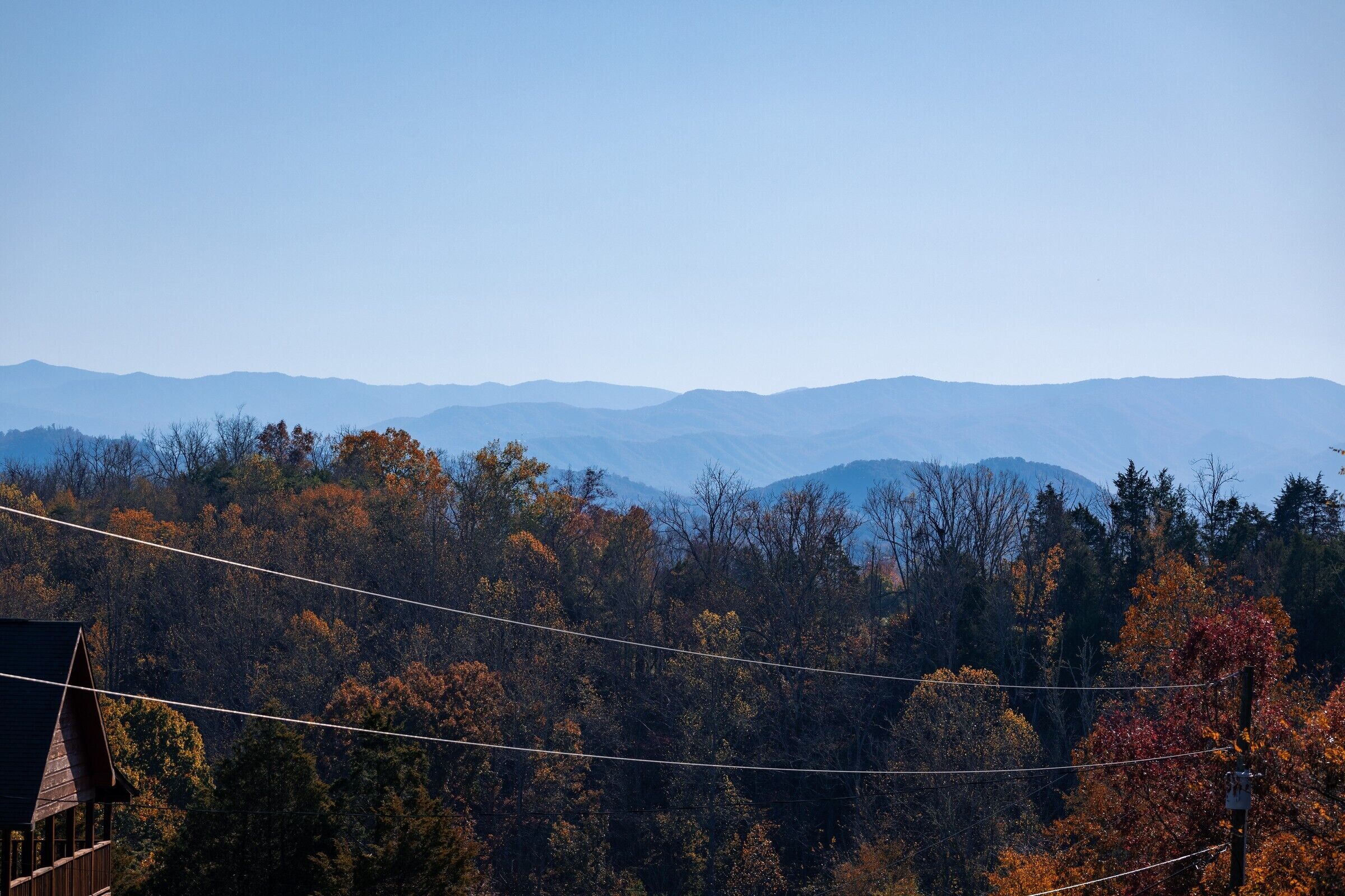 A mountainous landscape with autumn foliage and a house in the foreground.