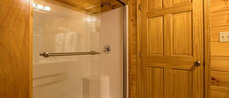 Ein Badezimmer mit Holzwänden, einer Glaskabine für die Dusche und einer Holztür.