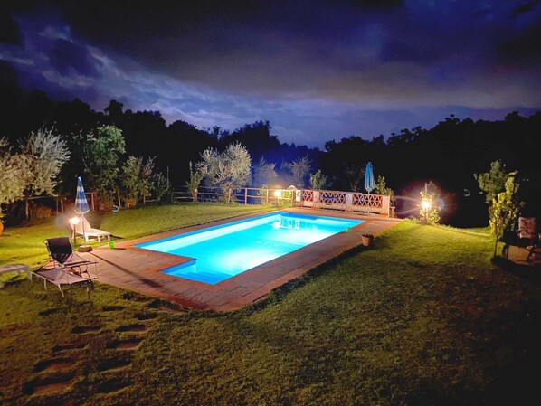 A rectangular swimming pool with a wooden deck and a fence, surrounded by a grassy lawn and trees. - Villa in Toscana - Reggello con Piscina, Wi-Fi, Giardini. (Reggello)
