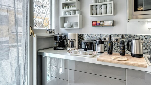 Een moderne keuken met witte kasten, een koffiehoek en een decoratief raam.