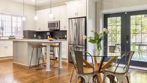 Una cocina moderna con armarios blancos, electrodomésticos de acero inoxidable y una isla central con taburetes.