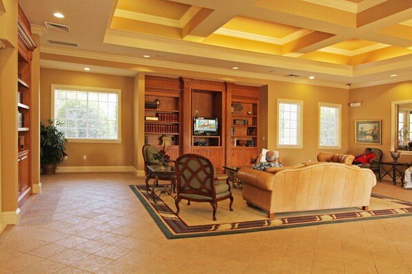 A spacious living room with a fireplace, a large sofa, a coffee table, and a bookshelf.