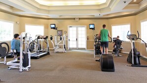 Un gimnasio con cintas de correr, elípticas y equipo de pesas.