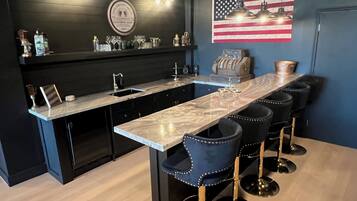 Una cocina moderna con encimera de mármol, taburetes negros y una decoración con la bandera estadounidense.