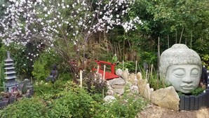 A serene garden with a large Buddha statue, a pagoda, and a red bridge. - Beautiful 5 rm.Hardwood Austin Home! (Austin)