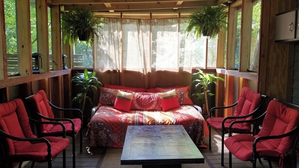 A cozy room with a bed, a table, and red chairs. There are plants and a window with curtains. - Beautiful 5 rm.Hardwood Austin Home! (Austin)