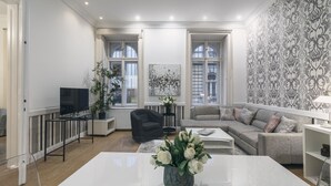 Un soggiorno moderno con una TV a schermo piatto, un divano, un tavolino da caffè e un vaso decorativo con fiori.