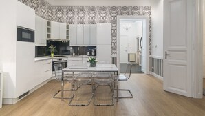 Una cucina moderna con mobili bianchi, un'isola centrale con sedie e carta da parati decorata.