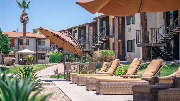 A hotel courtyard with outdoor seating, a palm tree, and a staircase leading to an upper level. - 133 Fully Furnished, amenities galore! (Scottsdale)