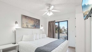 A bedroom with a bed, bedside tables, a ceiling fan, a painting, a TV, and a view of the outdoors. - 133 Fully Furnished, amenities galore! (Scottsdale)