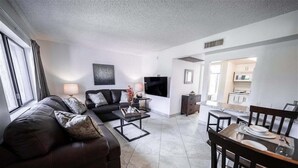 A modern living room with a sofa, coffee table, TV, and dining area. - 240 Relaxing Scottsdale Stay – Pet-Friendly, Park Views & Putting Green (Scottsdale)