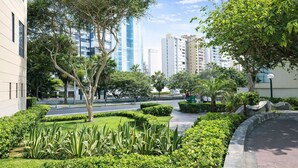 Un espace urbain aménagé, avec des bâtiments modernes, une promenade dallée et de la verdure.