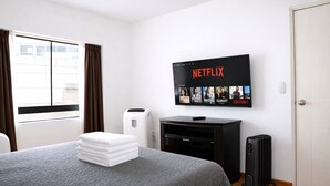 Une chambre d’hôtel équipée d’un lit, d’un téléviseur fixé au mur diffusant Netflix, d’un radiateur électrique et d’un chauffage central.