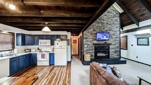A modern kitchen with dark blue cabinets, white appliances, and a stone accent wall.