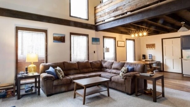 A spacious living room with a sectional sofa, a coffee table, and a wooden ceiling.
