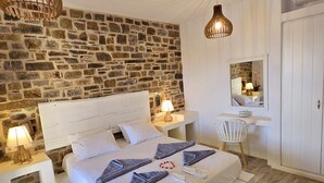 Ein Schlafzimmer mit Steinwand, einem weißen Bett, Holzboden und zwei Pendelleuchten.