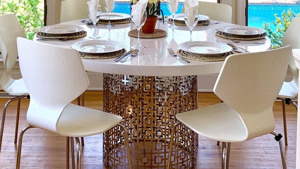 A dining area with a round table, white chairs, and a decorative centerpiece. - Stylish East Hampton Village Retreat- Heated Pool and Sauna, Steps to Village (East Hampton)