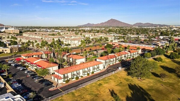 A residential area with modern buildings, a parking lot, and a mountain in the background.