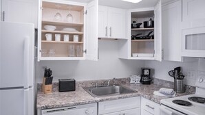 Een moderne keuken met witte kasten, een granieten aanrecht, een geïntegreerde gootsteen en een fornuis.