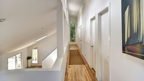 Ein modernes Interieur mit Holzboden, weißen Wänden und einer Treppe, die zu einer oberen Ebene führt.