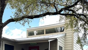 Une maison à deux étages avec une porte rouge, un balcon et un escalier menant à l’étage supérieur.