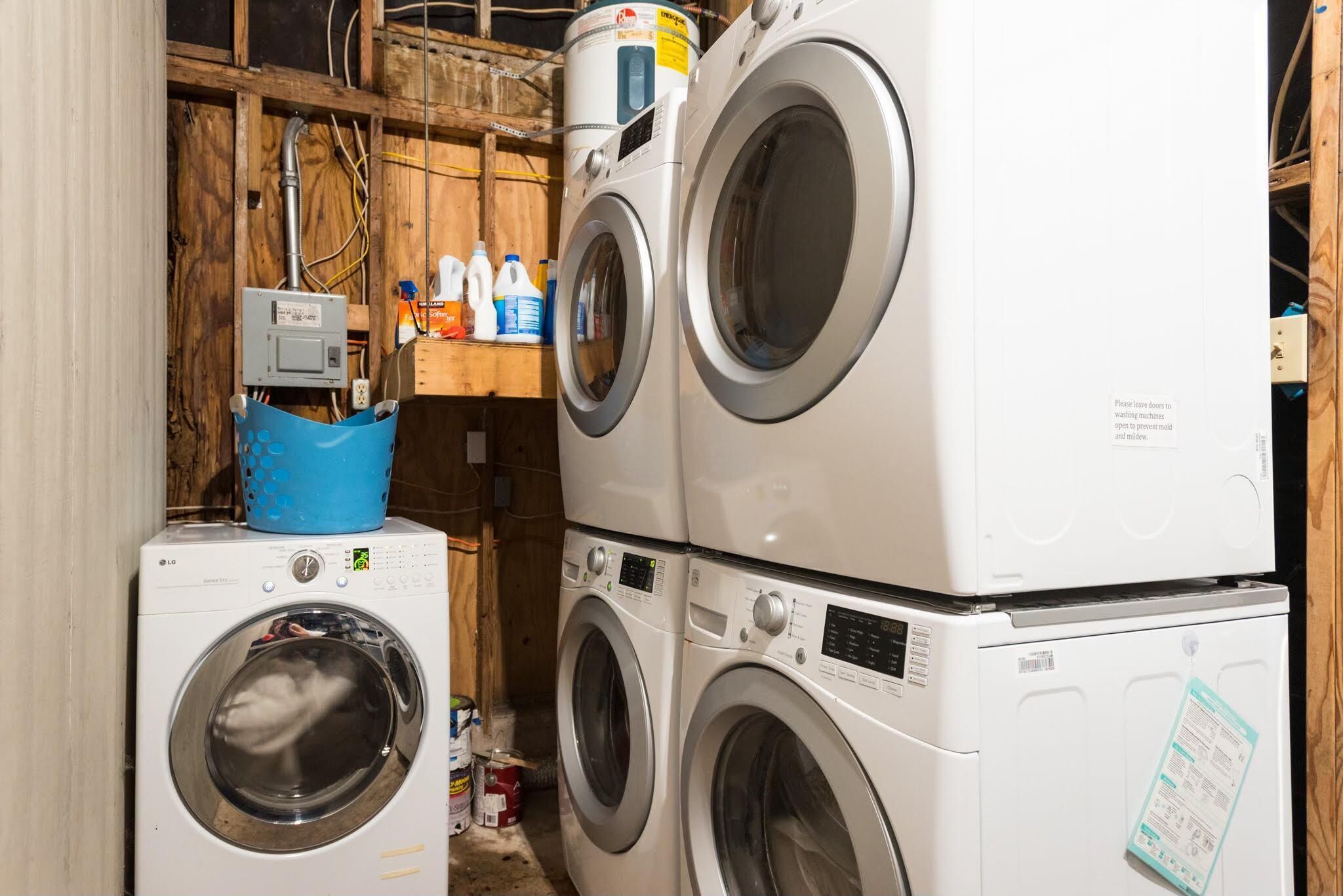 Stacked front-loading washing machines in a utility room with wooden walls and electrical outlets.
