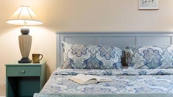 A bedroom with a bed, a nightstand, a lamp, and a book.