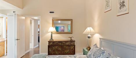 A bedroom with a bed, bedside lamps, a dresser, and a mirror.