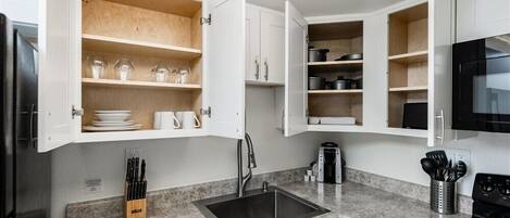 A kitchen with white cabinets, a granite countertop, a black sink, and a stove.