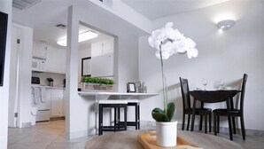 A modern kitchen with white cabinets, a welcome sign, a dining table with chairs, and a potted orchid. - 218 Scottsdale Charmer: Pool, Patio, and Perfectly Located (Scottsdale)