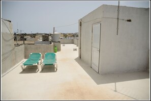 Relax on the rooftop terrace with a stunning view of the urban landscape, featuring two lounge chairs and a water dispenser.