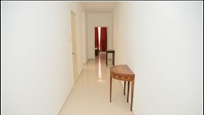 Un pasillo estrecho con una mesa de madera y una puerta al final.